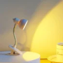 Compact warm mini lamp clipped onto a paperback book page providing bright glare-free reading light.