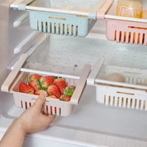 Hanging translucent fridge baskets clipped onto a glass refrigerator shelf holding fresh eggs and fruit.