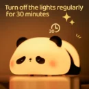 Cute silicone panda lamp glowing with warm dimmable light on a cozy bedside table.