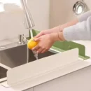 Grey silicone sink splash guard attached securely to the front edge of a kitchen sink counter.