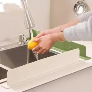 Grey silicone sink splash guard attached securely to the front edge of a kitchen sink counter.