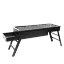 Black folding charcoal BBQ grill with a slide-out drawer ash catcher set up on a wooden patio table.
