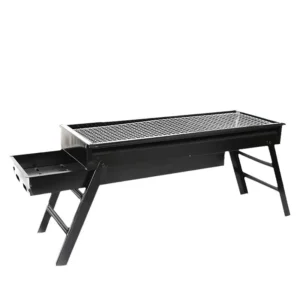 Black folding charcoal BBQ grill with a slide-out drawer ash catcher set up on a wooden patio table.