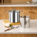 Stainless steel frying pan with a wire mesh frying basket lifting crispy chicken wings out of hot cooking oil.