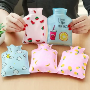 Small pink pocket-sized mini hot water bag with a secure leak-proof screw cap resting on a soft cozy blanket.