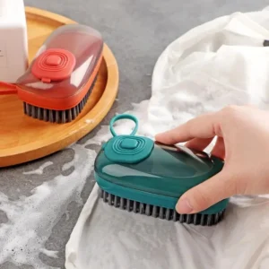 Minimalist blue and white cleaning brush with an integrated soap dispenser button sitting on a clean kitchen counter.