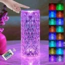 Diamond-cut acrylic crystal lamp glowing with a warm rose pattern light reflection on a wooden bedside table.