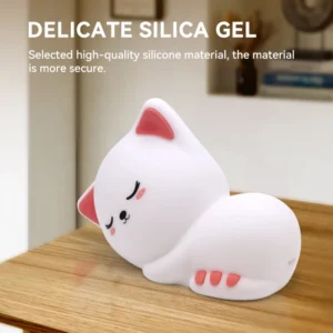 Adorable sleeping cat night light glowing with a warm soft ambient light inside a small wooden-style display dome on a bedside stand.