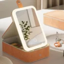 Elegant cream-colored textured makeup bag open on a marble vanity, showing illuminated makeup mirror and neatly arranged cosmetics.
