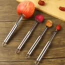 Stainless steel manual seed remover tool cleanly pulling out the center core and seeds of a fresh red apple on a kitchen island.